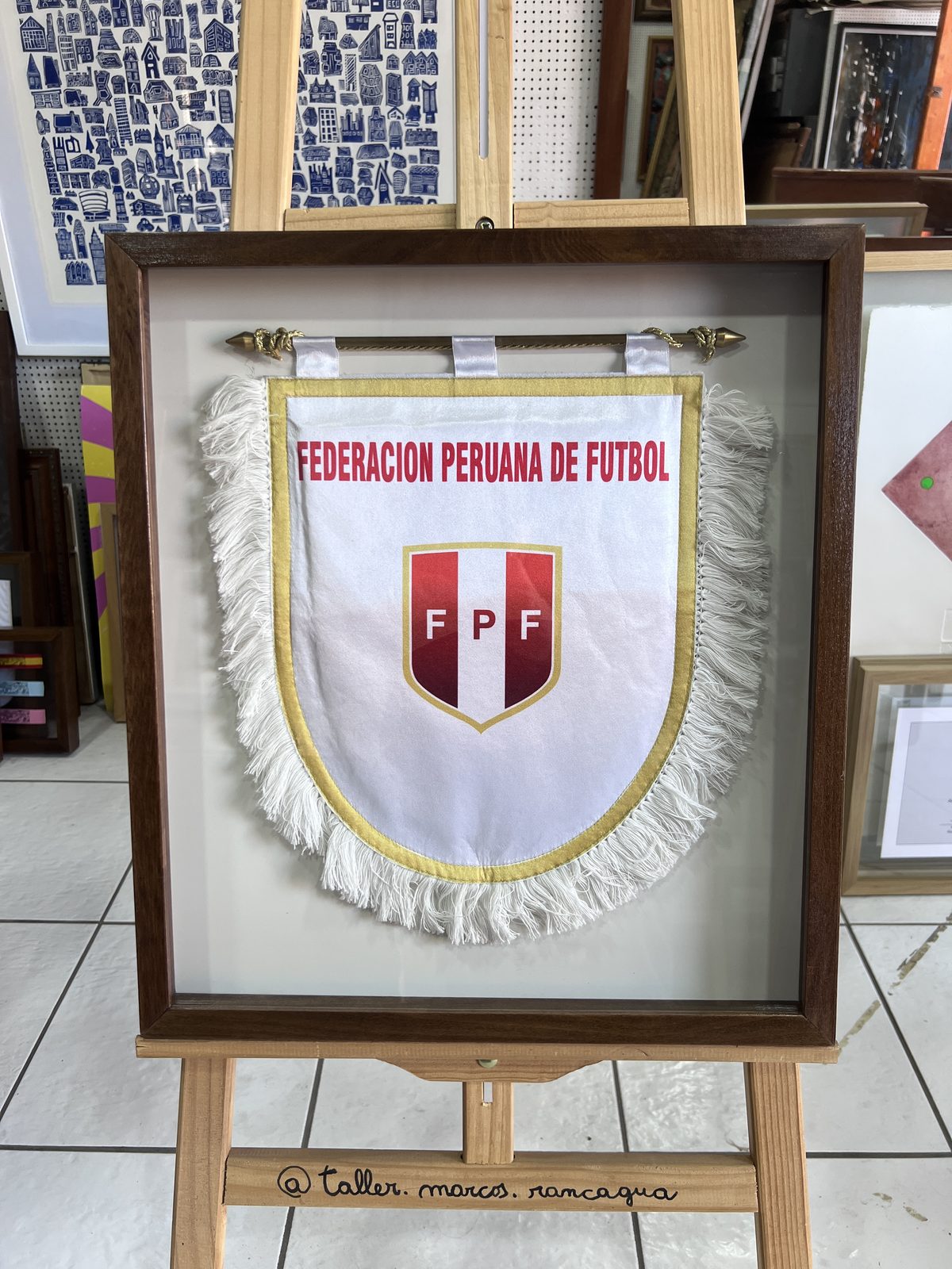 Banderín de la Federación Peruana de Fútbol enmarcado en cajón de madera oscura sobre fondo blanco